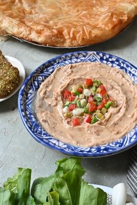 Plate of foul with tahini and vegetables on it