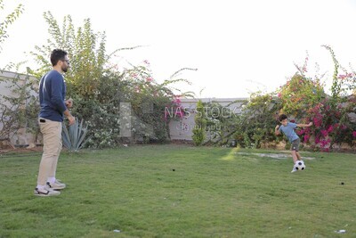 a father playing football with his son in the garden