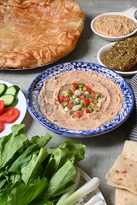 Plate of foul with tahini and vegetables on it