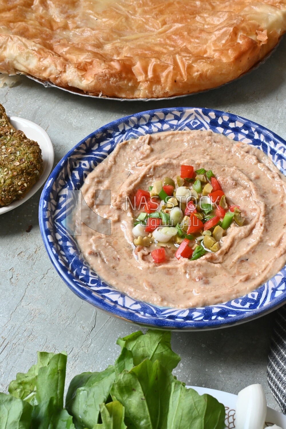 plate of foul with tahini and vegetables on it