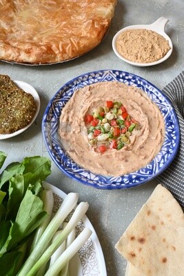 Plate of foul with tahini and vegetables on it