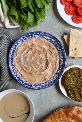 plate of foul with tahini and vegetables on it