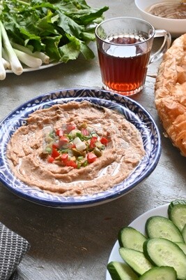 plate of foul with tahini and vegetables on it