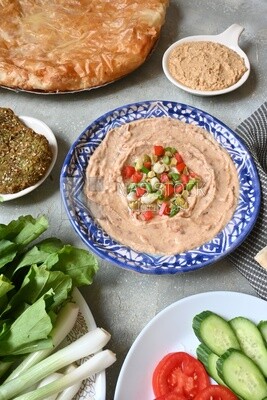 Plate of foul with tahini and vegetables on it