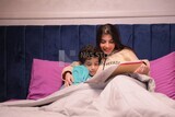 a woman reading a story to her son in bed