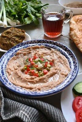 Plate of foul with tahini and vegetables on it