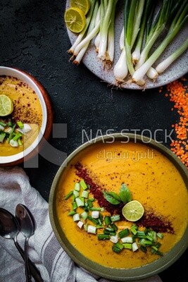 Plate of egyptian lentil soup with onion, lemon, and bread.