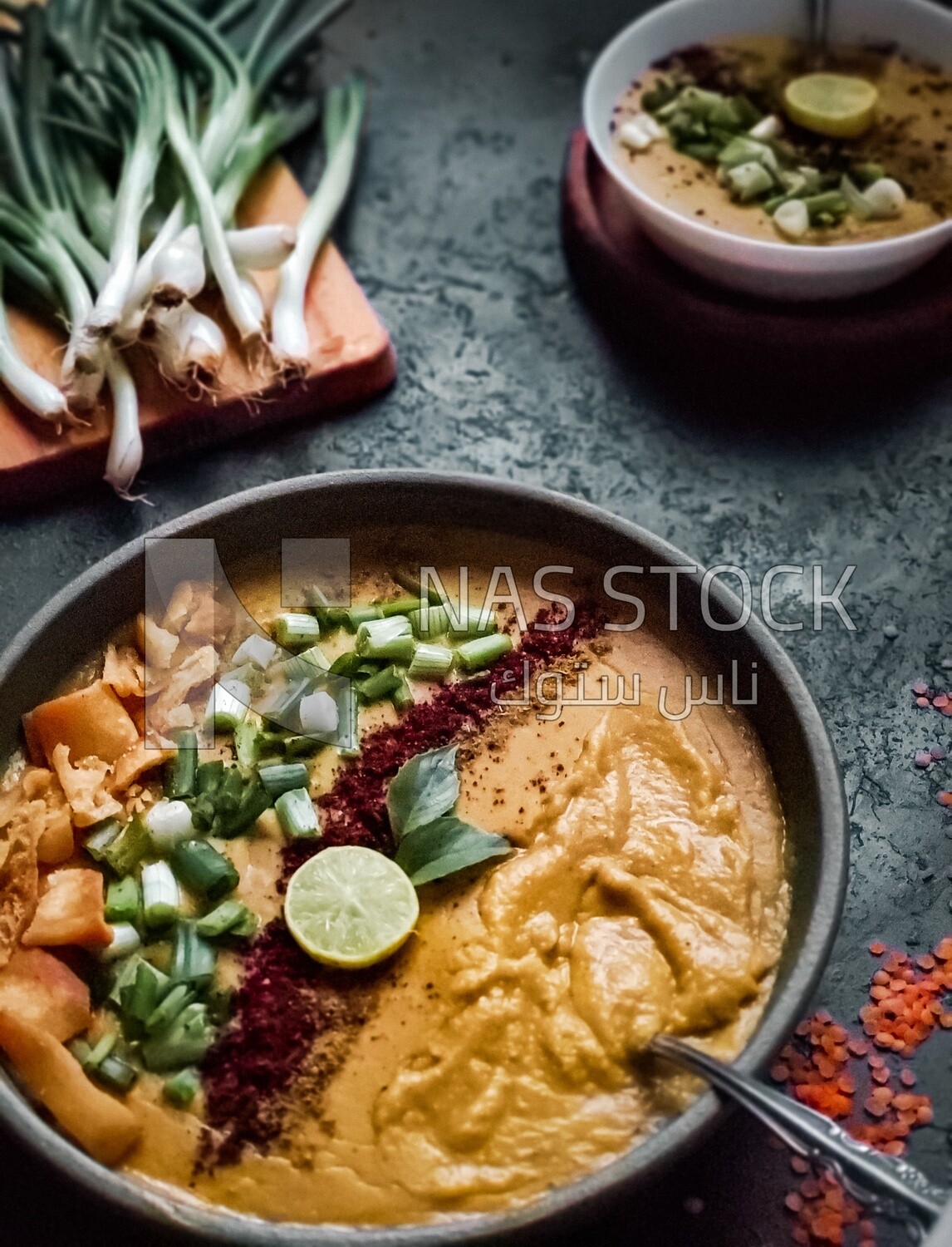Plate of egyptian lentil soup with onion, lemon, and bread