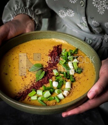 Plate of egyptian lentil soup with onion, lemon, and bread.