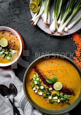 Plate of egyptian lentil soup with onion, lemon, and bread.