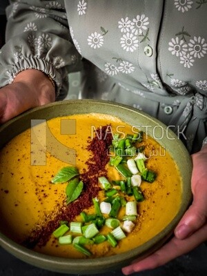 Plate of egyptian lentil soup with onion, lemon, and bread.