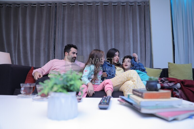 a family of four sitting on the sofa talking together