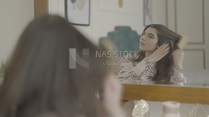 a woman sitting in front of the mirror brushing her hair