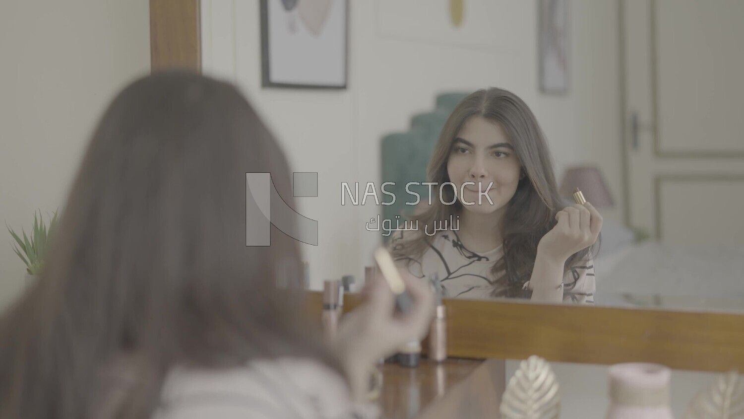 a woman sitting in front of the mirror putting on lipstick