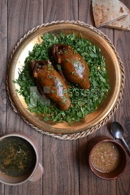 plate with stuffed pigeons beside soup and bread