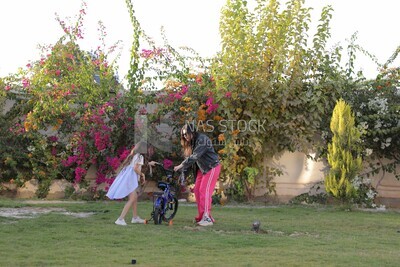 a woman helping her daughter ride a bike