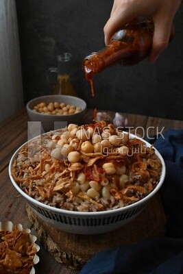 Hand puts spices on the koshary