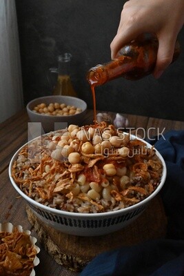 Hand puts spices on the koshary