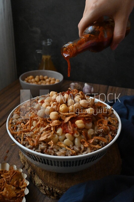 Hand puts spices on the koshary