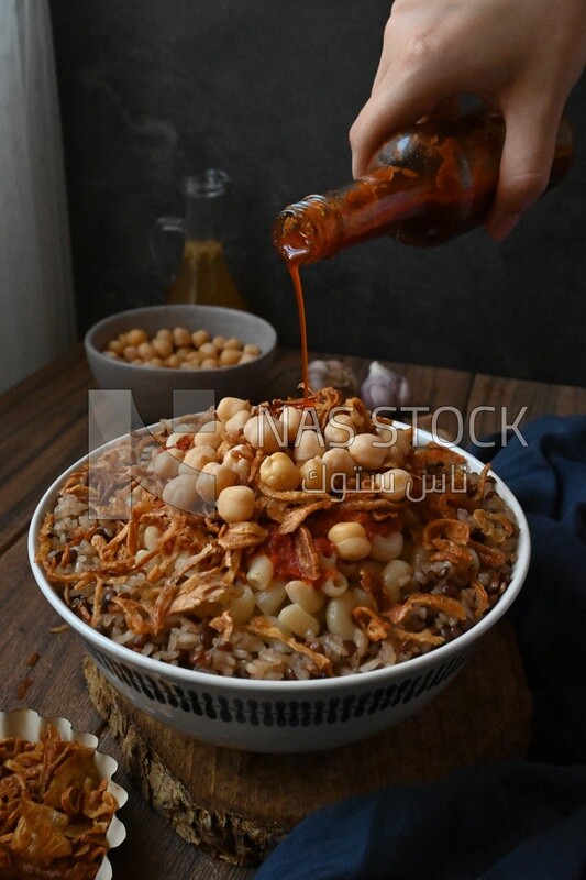 Hand puts spices on the koshary