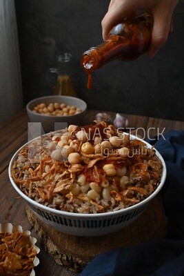 Hand puts spices on the koshary