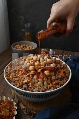 Hand puts spices on the koshary