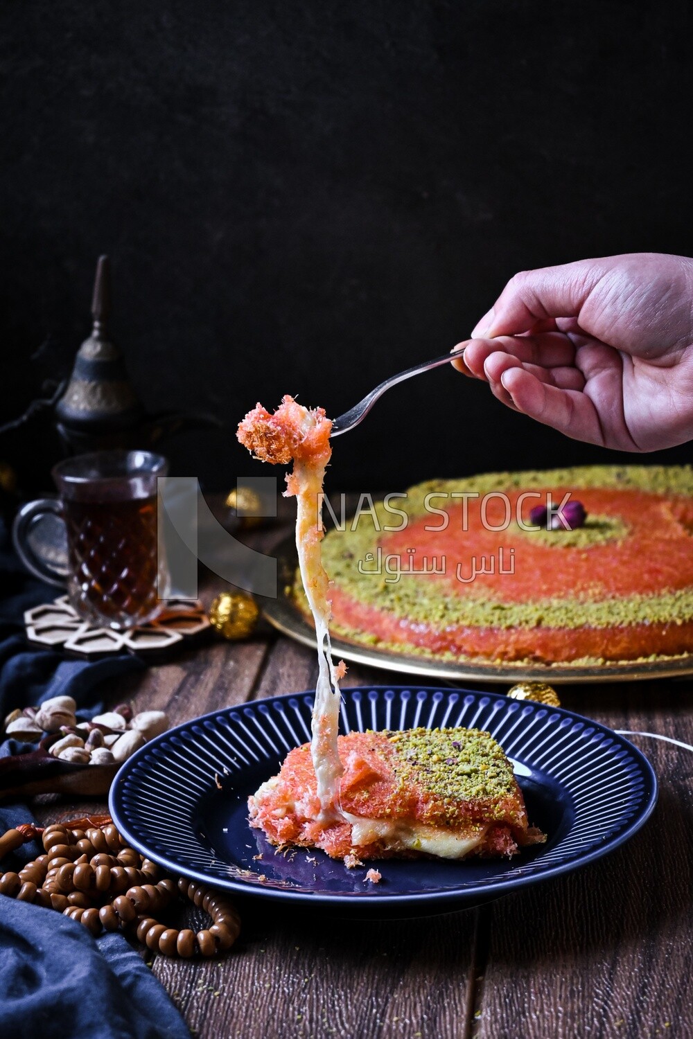 Hand holding fork and eating knafeh