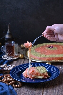 Hand holding fork and eating knafeh