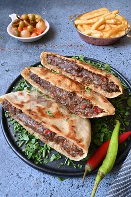 dish with hawawshi next to spicy pepper and fries