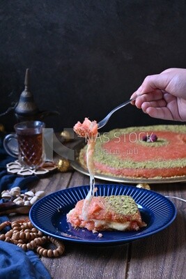 Hand holding fork and eating knafeh