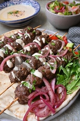 Dish with grilled kofta with tahini sauce on it