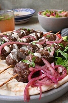 Dish with grilled kofta with tahini sauce on it