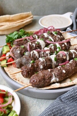Dish with grilled kofta with tahini sauce on it