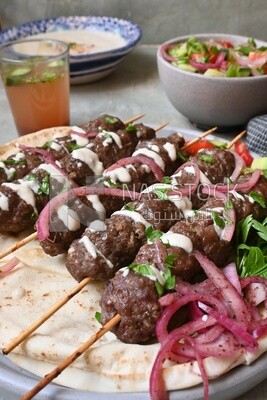 Grilled Dish with grilled kofta with tahini sauce on it