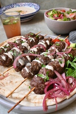 Dish with grilled kofta with tahini sauce on it