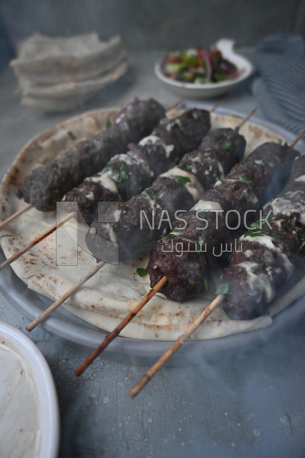 Dish with grilled kofta with tahini sauce on it
