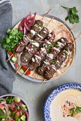 Dish with grilled kofta with tahini sauce on it