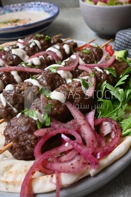 Dish with grilled kofta with tahini sauce on it
