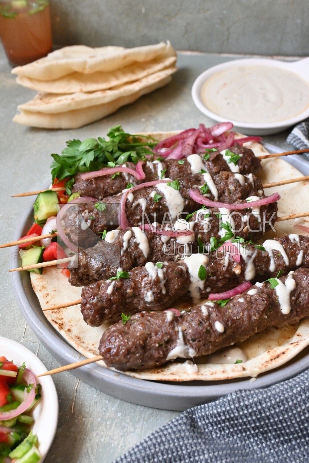 Dish with grilled kofta with tahini sauce on it