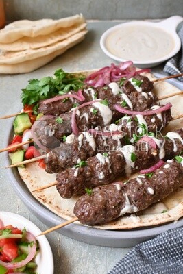 Dish with grilled kofta with tahini sauce on it