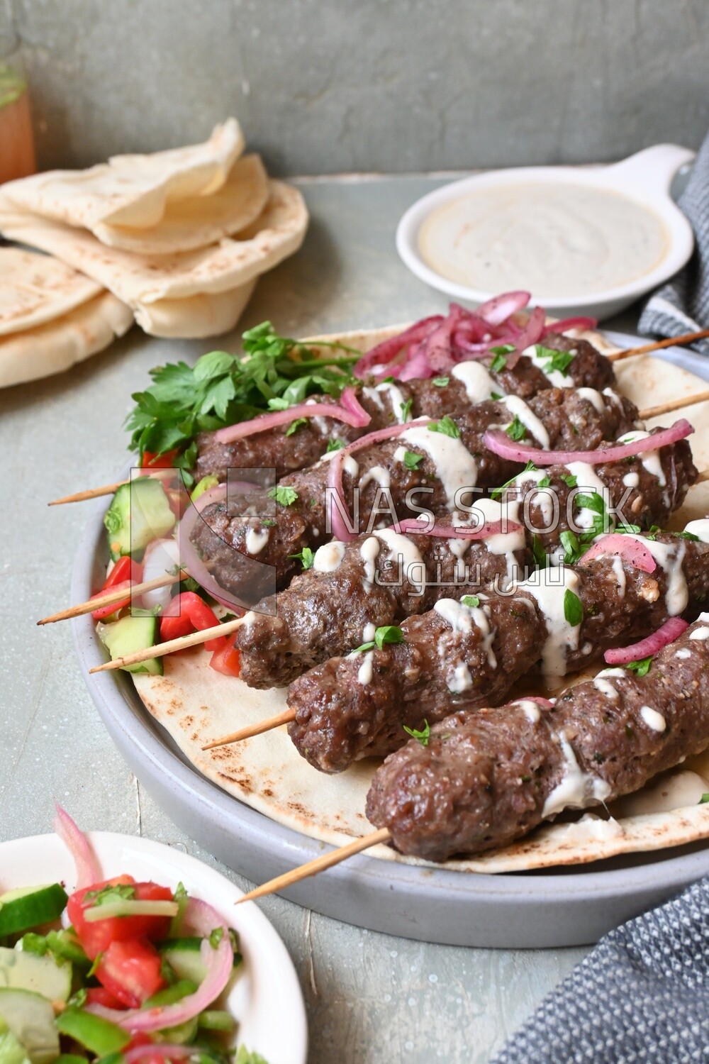 Dish with grilled kofta with tahini sauce on it