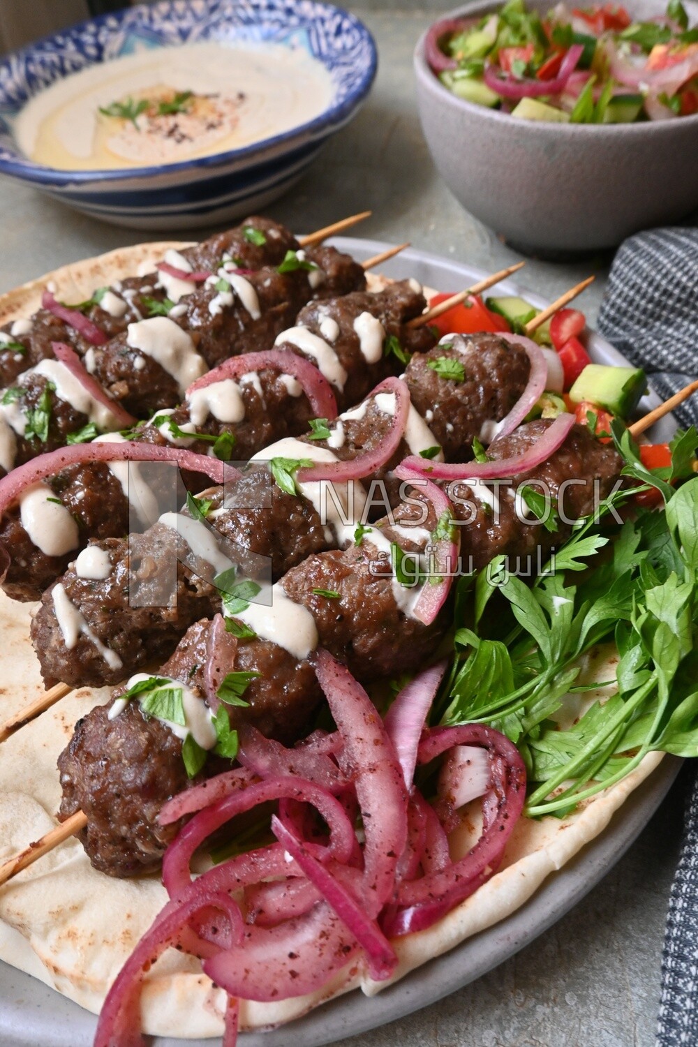 Dish with grilled kofta with tahini sauce on it