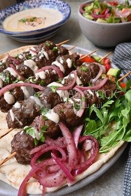 Dish with grilled kofta with tahini sauce on it