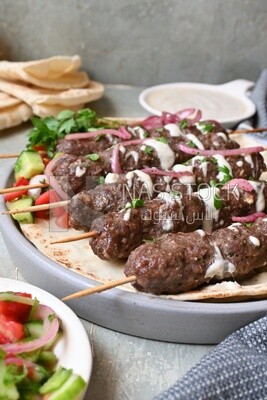Dish with grilled kofta with tahini sauce on it