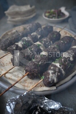 Dish with grilled kofta with tahini sauce on it