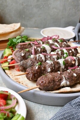 Dish with grilled kofta with tahini sauce on it