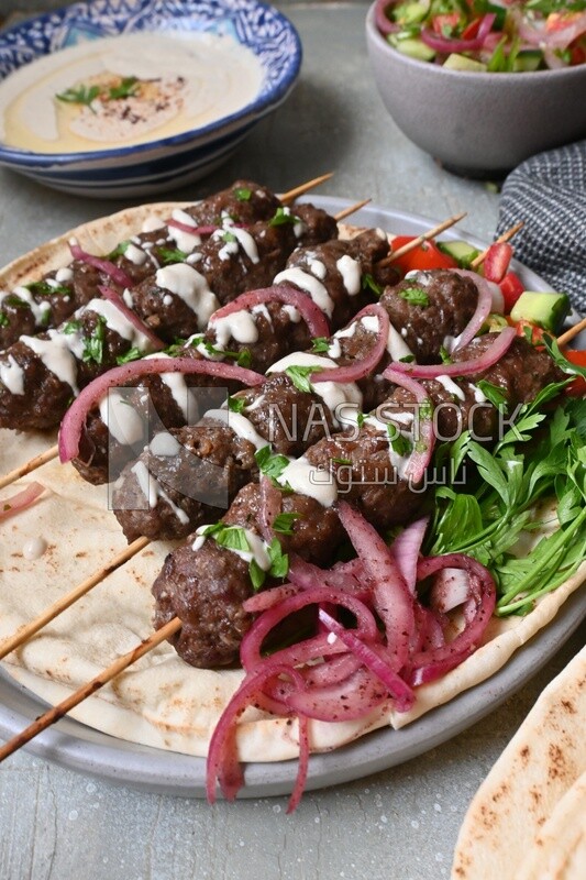 Dish with grilled kofta with tahini sauce on it