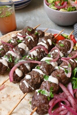 Dish with grilled kofta with tahini sauce on it