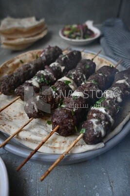 Dish with grilled kofta with tahini sauce on it