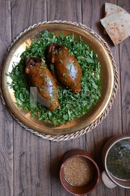 plate with stuffed pigeons beside soup and bread